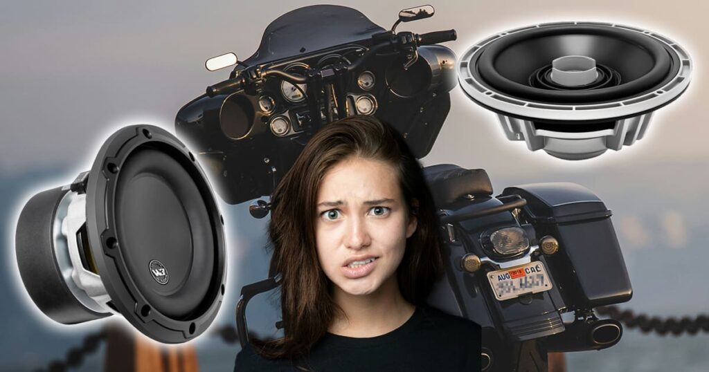 A lady in front of a large motorcycle with car audio speakers on each side, looking confused
